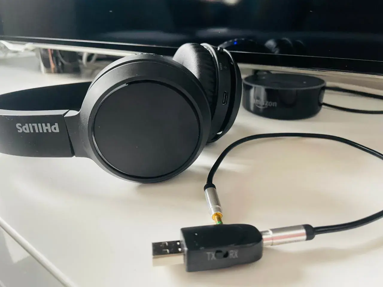 Czarne słuchawki Philips z adapterem audio TX/RX i Amazon Echo Dot.